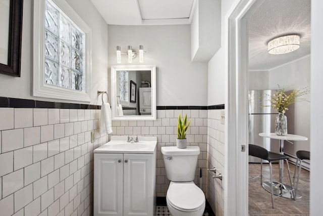 bathroom with toilet, crown molding, tile walls, and vanity