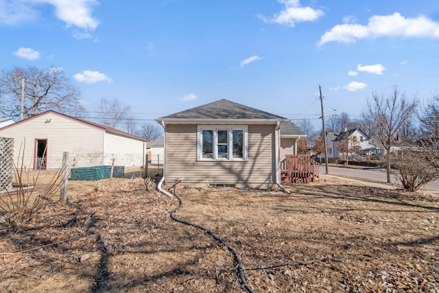 back of property with roof with shingles and fence