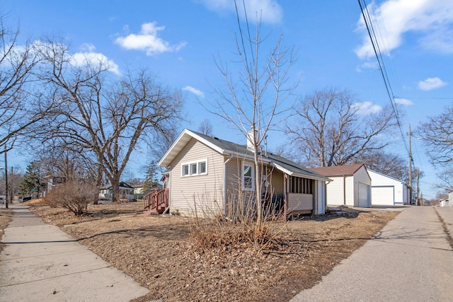 view of side of home with a garage, an outbuilding, and a chimney