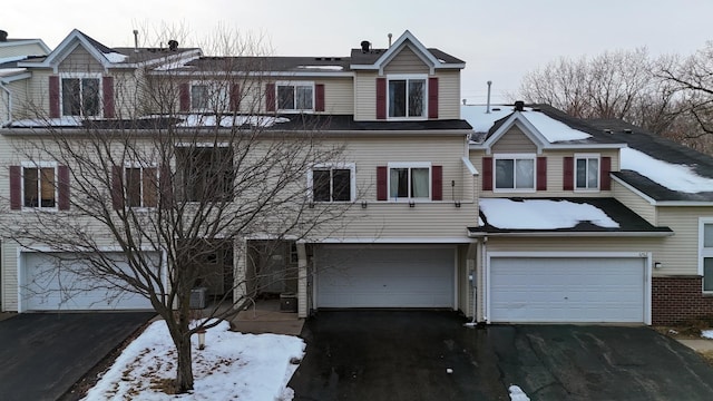 view of front of home with a garage, driveway, brick siding, and cooling unit