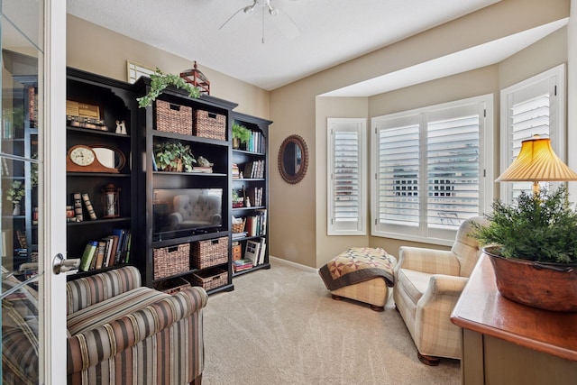 living area featuring carpet, ceiling fan, and baseboards