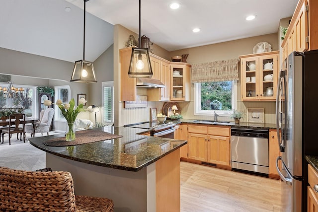 kitchen featuring appliances with stainless steel finishes, light wood-style floors, open floor plan, a sink, and dark stone counters