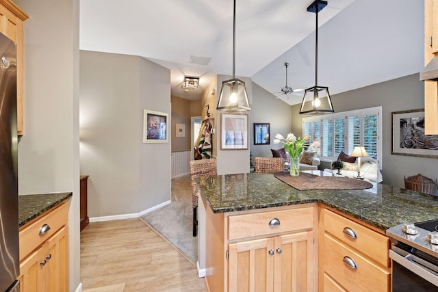 kitchen featuring lofted ceiling, open floor plan, dark stone countertops, and light brown cabinetry