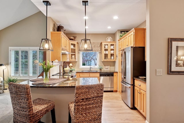 kitchen featuring light brown cabinetry, appliances with stainless steel finishes, a sink, a peninsula, and under cabinet range hood