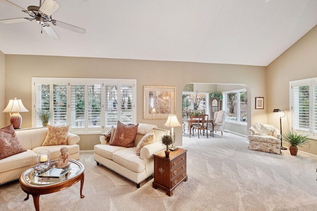 living area featuring arched walkways, a ceiling fan, light carpet, vaulted ceiling, and baseboards