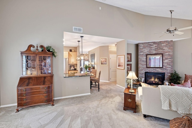 living area with baseboards, visible vents, a ceiling fan, light colored carpet, and a brick fireplace