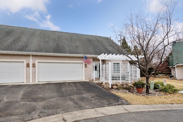 view of front of house featuring a garage, driveway, roof with shingles, and stucco siding