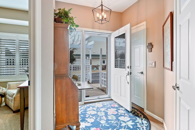 foyer featuring baseboards, a notable chandelier, and wood finished floors