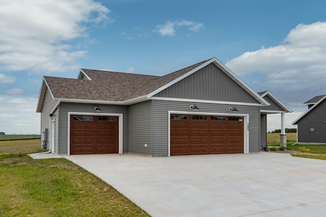 view of front of house featuring an attached garage, driveway, a shingled roof, and a front yard