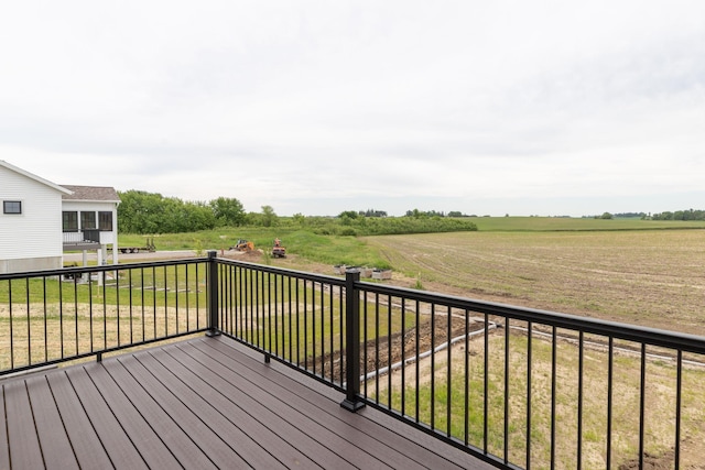 wooden terrace with a rural view and a yard