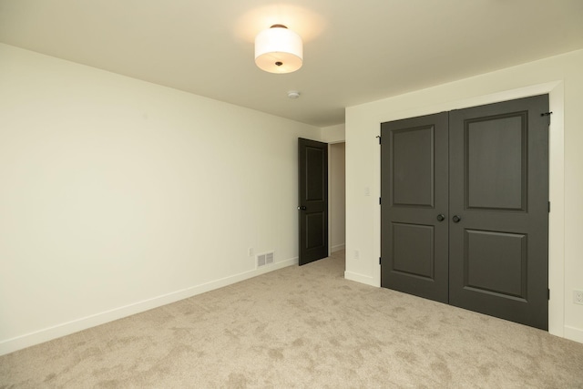 unfurnished bedroom featuring baseboards, a closet, visible vents, and light colored carpet