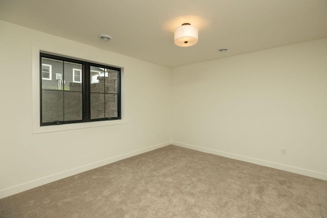 empty room featuring baseboards and light colored carpet