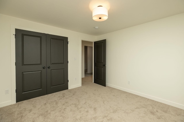 unfurnished bedroom featuring light carpet, a closet, and baseboards