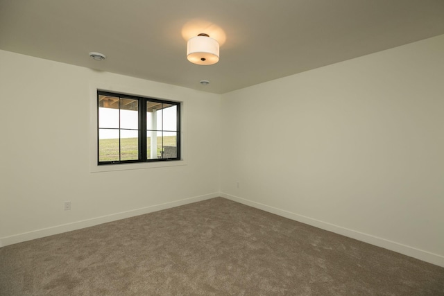 unfurnished room with dark colored carpet and baseboards