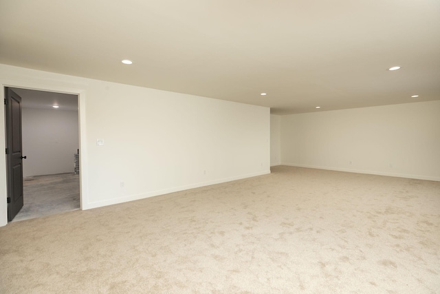 spare room with baseboards, recessed lighting, and light colored carpet