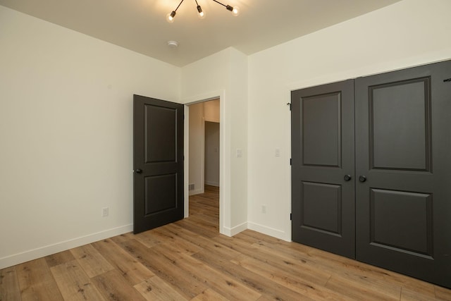 unfurnished bedroom with light wood-type flooring, baseboards, and a closet