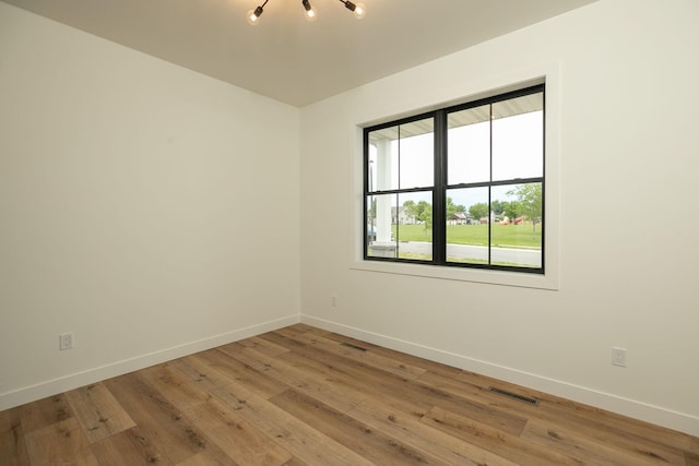 empty room with light wood finished floors, baseboards, and visible vents