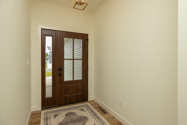 foyer entrance featuring visible vents, light wood-style flooring, and baseboards