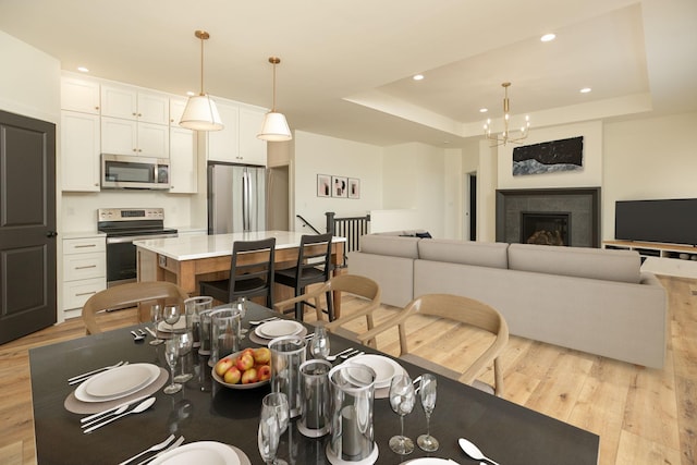 interior space with light wood finished floors, a fireplace, a raised ceiling, and recessed lighting