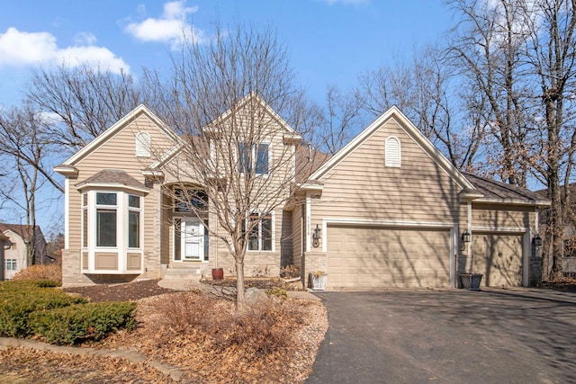 traditional home featuring brick siding, driveway, and an attached garage