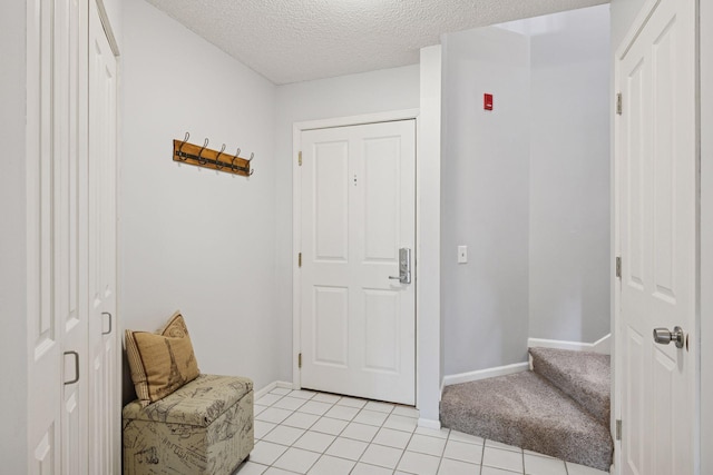 foyer entrance with baseboards, light colored carpet, a textured ceiling, and light tile patterned flooring