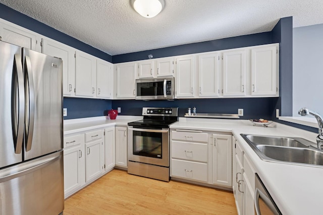 kitchen featuring stainless steel appliances, light wood-type flooring, white cabinets, and a sink