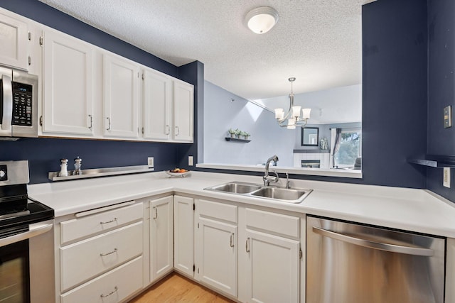 kitchen featuring white cabinetry, stainless steel appliances, a sink, and light countertops