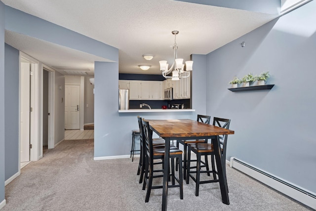 carpeted dining area with a baseboard radiator, a sink, a textured ceiling, a chandelier, and baseboards