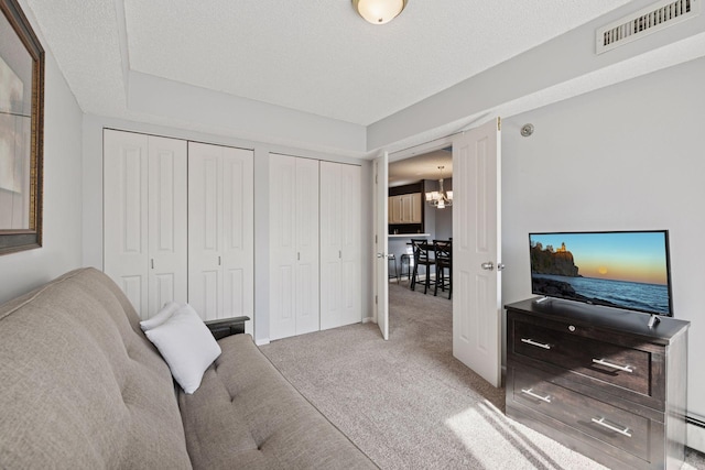 bedroom with carpet floors, a notable chandelier, multiple closets, visible vents, and a textured ceiling