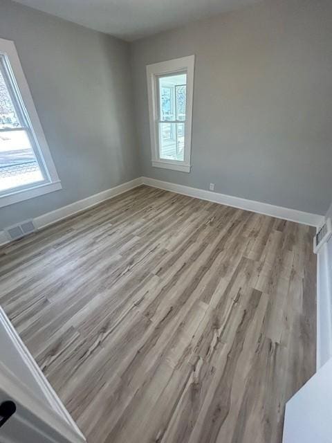 unfurnished room with visible vents, baseboards, and wood finished floors