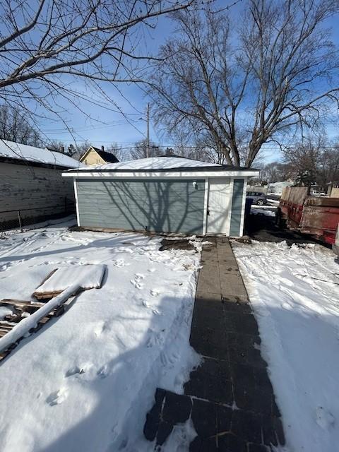 snow covered structure with an outbuilding