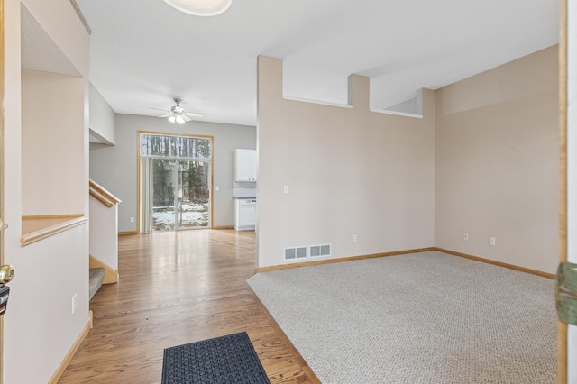 unfurnished room with visible vents, baseboards, ceiling fan, stairs, and light wood-style floors