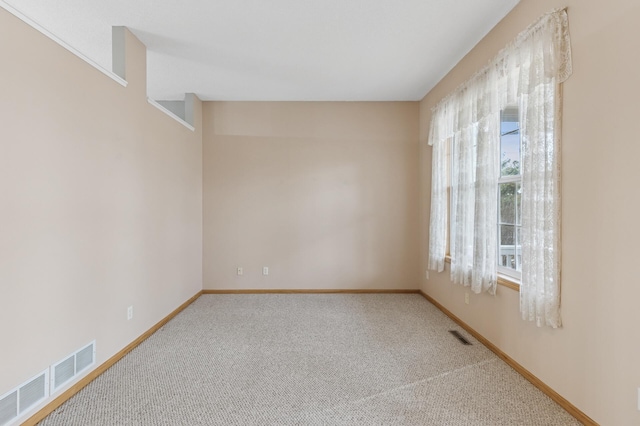 empty room with visible vents, baseboards, and carpet