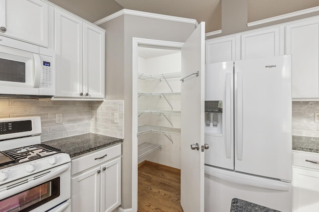 kitchen featuring white appliances, dark stone countertops, wood finished floors, decorative backsplash, and white cabinetry