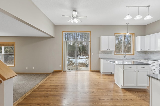 kitchen featuring a sink, decorative backsplash, plenty of natural light, and white cabinets