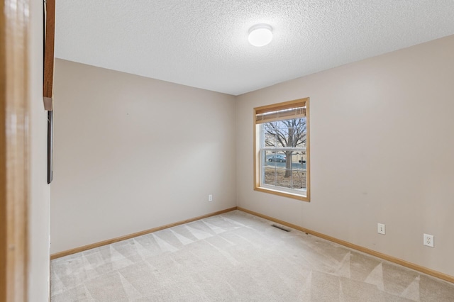 empty room featuring a textured ceiling, baseboards, visible vents, and light carpet