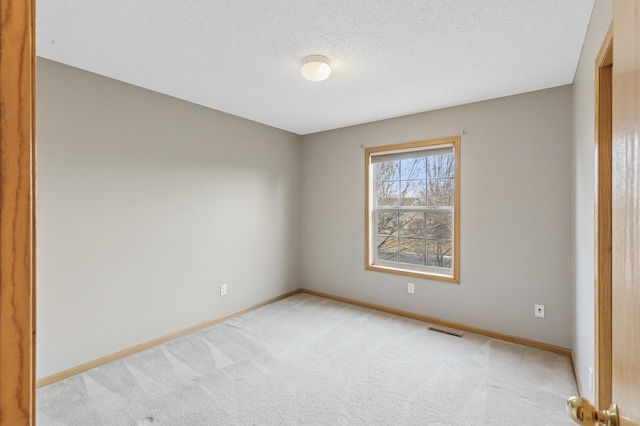 unfurnished room featuring visible vents, light colored carpet, a textured ceiling, and baseboards