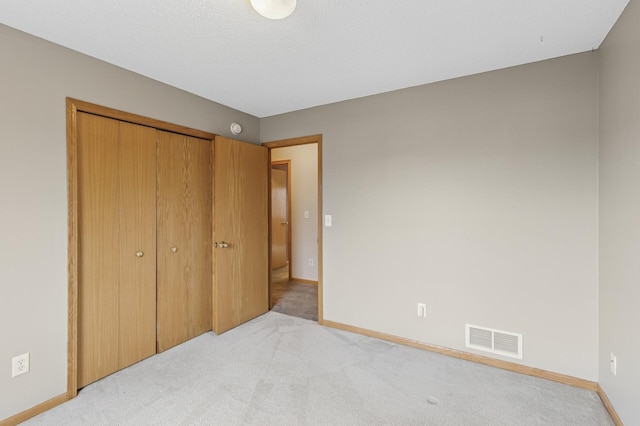 unfurnished bedroom featuring visible vents, light carpet, baseboards, and a closet