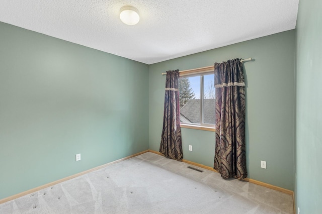 spare room featuring visible vents, baseboards, a textured ceiling, and carpet flooring