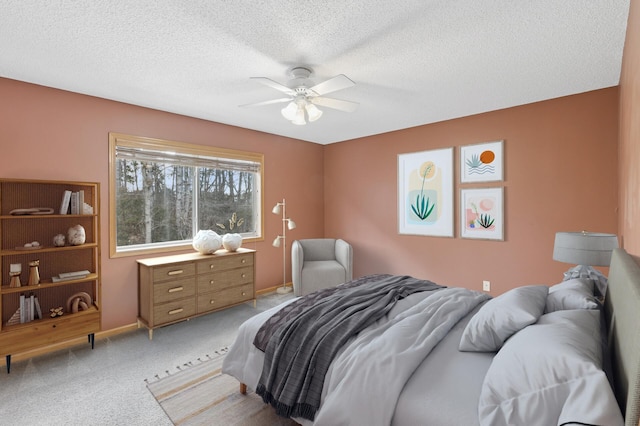 carpeted bedroom featuring ceiling fan, baseboards, and a textured ceiling