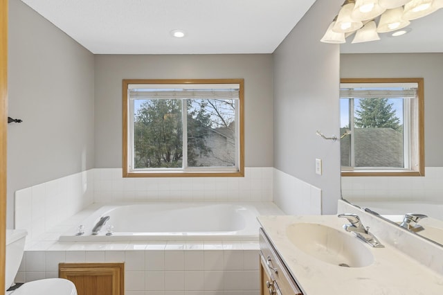 bathroom featuring a healthy amount of sunlight, vanity, and a garden tub