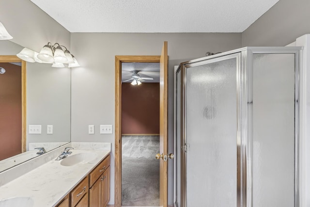 bathroom with a textured ceiling, double vanity, a stall shower, and a sink