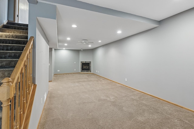 unfurnished living room featuring a glass covered fireplace, recessed lighting, stairway, light colored carpet, and ceiling fan