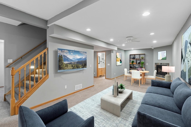 living area with visible vents, a tiled fireplace, stairway, light colored carpet, and recessed lighting