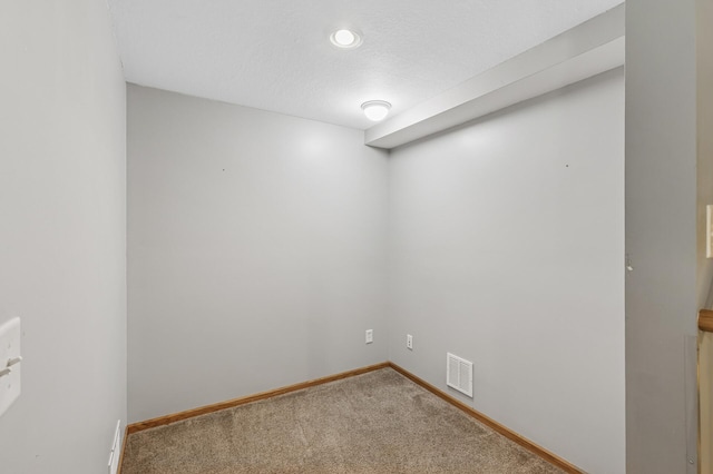 empty room featuring baseboards, visible vents, carpet floors, and a textured ceiling