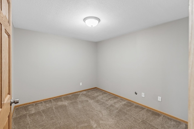 carpeted spare room featuring a textured ceiling and baseboards