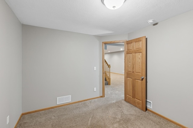 unfurnished bedroom with visible vents, baseboards, carpet, and a textured ceiling