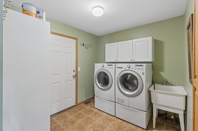 laundry area with light tile patterned flooring, cabinet space, baseboards, and washer and clothes dryer