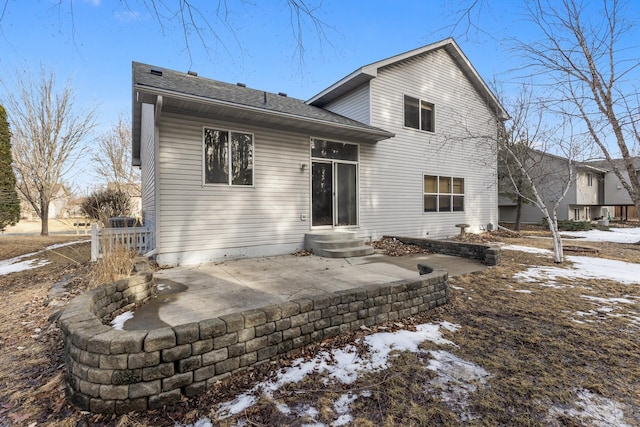 snow covered back of property featuring a patio and entry steps