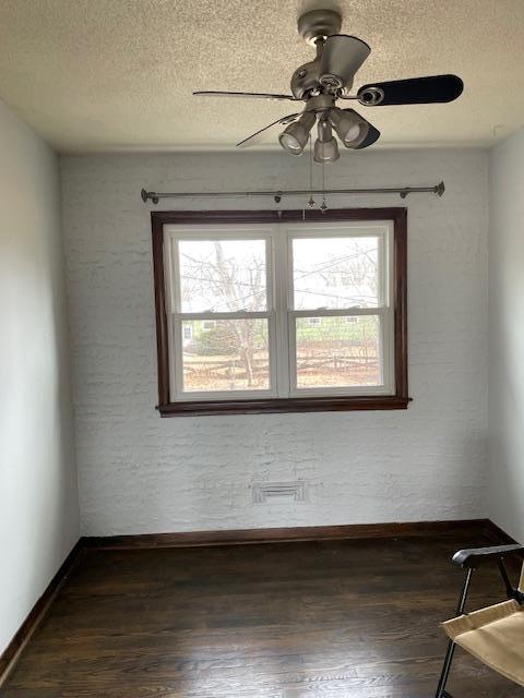 spare room featuring dark wood-style floors, ceiling fan, a textured ceiling, and baseboards